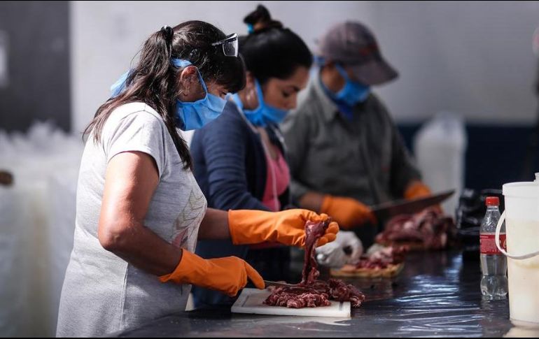 Mujeres cortan carne en la localidad Rafael Castillo en Buenos Aires, donde elementos del Ejército repartieron tres mil raciones de alimentos. EFE/J. Roncoroni