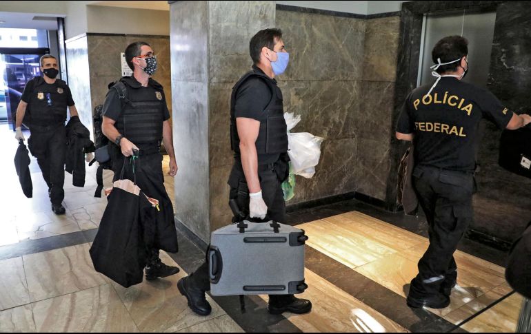 Policías federales cargan con lo que podría ser evidencia contra Wilson Witzel. AFP/F. Motta