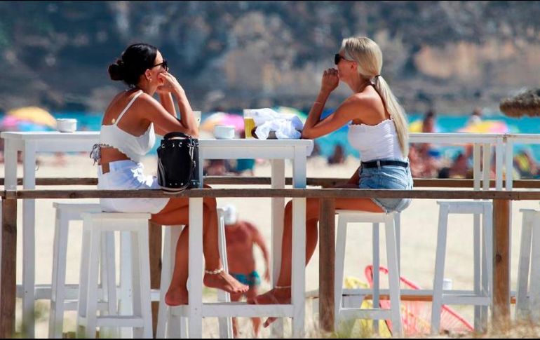 Dos turistas en una terraza disfrutan de un soleado día en la playa de Los Lances, en Tarifa, España. EFE/A. Carrasco