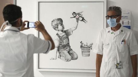 La pintura en blanco y negro muestra a un niño sentado en el piso jugando con una muñeca de enfermera superheroína. AP / ARCHIVO