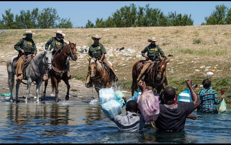 Agentes fronterizos a caballo hacen frente a migrantes. AFP/P. Ratje
