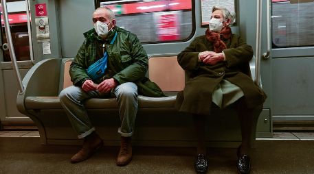 Una pareja de la tercera edad protegida con cubrebocas viaja en el metro de Milán. AFP/M. Medina