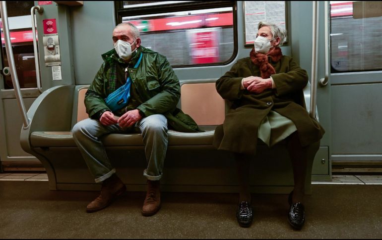 Una pareja de la tercera edad protegida con cubrebocas viaja en el metro de Milán. AFP/M. Medina