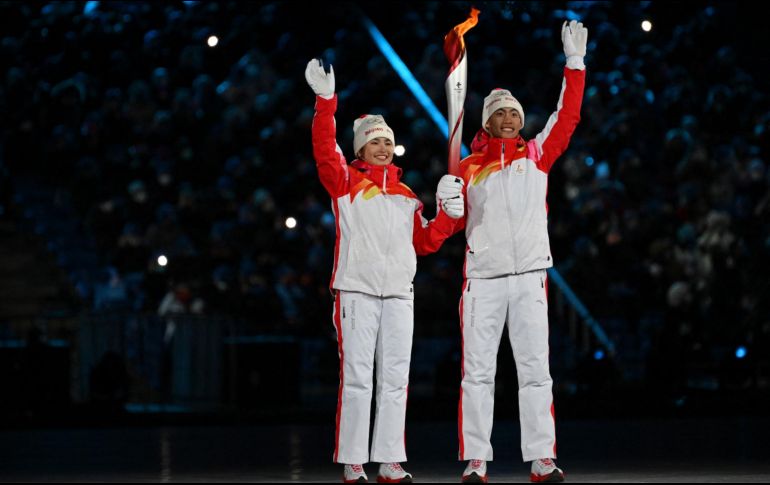 Los atletas portadores de la antorcha, los chinos Dinigeer Yilamujian (I) y Zhao Jiawen la sostienen durante la ceremonia de apertura. AFP / B. Stansall