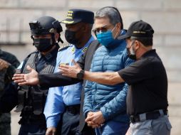 Juan Orlando Hernández acompañado por elementos de seguridad en su extradición. EFE/H. Espinoza
