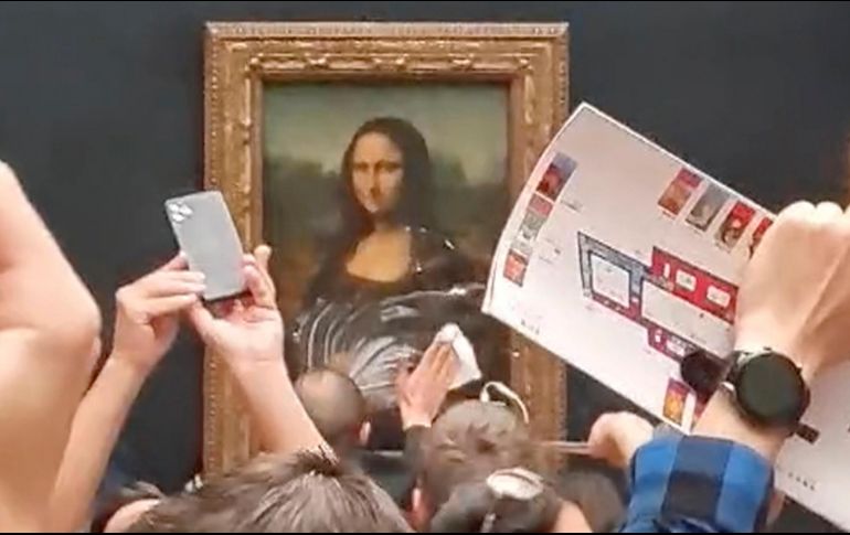 Aunque no hay imágenes del momento en que hombre lanza la tarta, las instantáneas de los visitantes permiten ver al personal del Louvre recogiendo los restos. AP