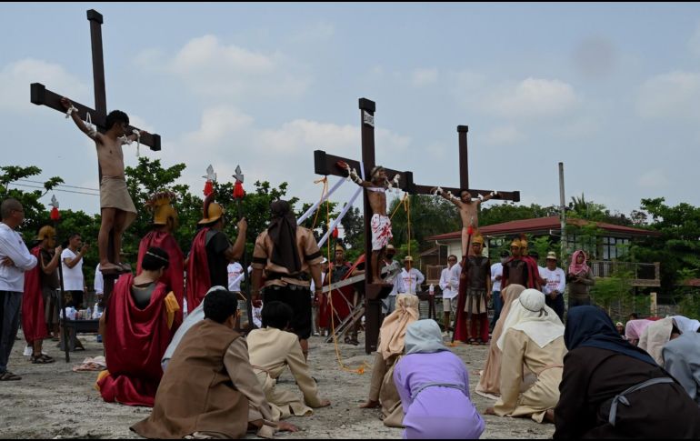 Al final del desfile, tres personas fueron escoltadas por hombres vestidos de romanos y fueron amarrados a cruces de madera. AFP / J. Sta Rosa