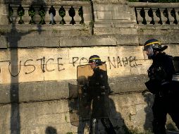Policías patrullando junto a un grafitti con la leyenda 