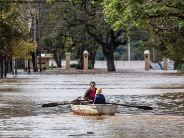 Una mujer acompañada de un niño conduce una embarcación por una calle inundada este lunes en Concordia (Argentina).  EFE/ Ignacio Jesús Rollano